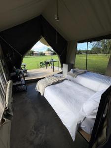 two beds in a tent with a view of a field at Kameeldoring Camping & Tented Chalets in Kakamas