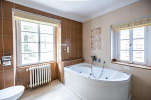 a bathroom with a tub and a toilet and windows at Hotel Metamorphis in Prague +97 photos