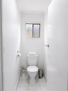 a white bathroom with a toilet and a window at The Pine Rest - Spacious & Central Haven in Brendale +13 photos