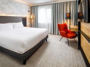 a hotel room with a bed and a chair at Mercure Birmingham West Hotel in West Bromwich