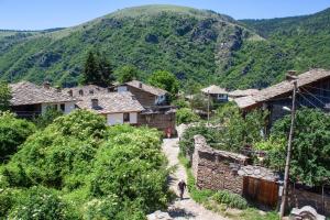 a village with a mountain in the background at Kruchma Bratyata Guest House in Kovačevica