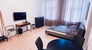 a living room with a bed and a table and a television at Hostel Kamienica 9 in Sosnowiec
