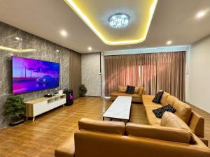 a living room with couches and a large screen tv at Honey Bliss Pool Villa in Hat Yai