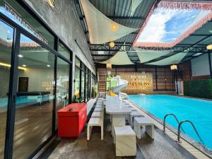 a pool with a table next to a swimming pool at Honey Bliss Pool Villa in Hat Yai