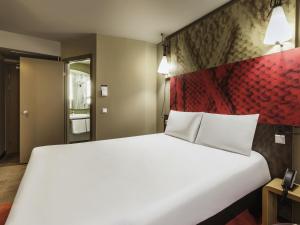 a bedroom with a large white bed with a red headboard at ibis Tbilisi Stadium in Tbilisi City +90 photos
