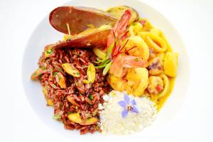 a white plate of food with rice and shrimp at Hotel Spa Nau Royal in Camburi