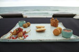 a tray of food on a table near the ocean at Hotel Spa Nau Royal in Camburi