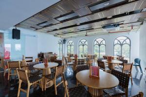 a dining room with tables and chairs and windows at Oyster Bay Vũng Tàu - Seaside Pool Escape in Vung Tau