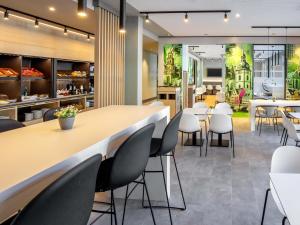 a restaurant with a long table and white chairs at B&B HOTEL Wertheim in Wertheim