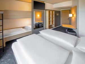 a hotel room with two beds and a desk at B&B HOTEL Wertheim in Wertheim