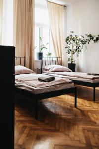 two beds in a room with wooden floors at Hostel Kamienica 9 in Sosnowiec