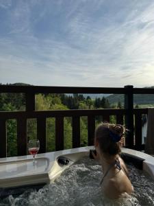 a woman in a hot tub with a glass of wine at Apartamenty Wilcza Knieja in Zawóz