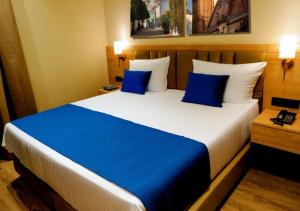 a bedroom with a large bed with blue pillows at Hotel Fortune Plaza in Karnal
