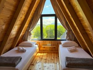 two beds in a room with a large window at Maple Valley in Žabljak