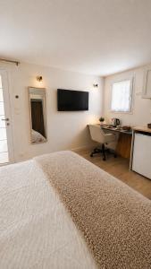 a bedroom with a bed and a desk and a television at Studio Cosy in Coussergues