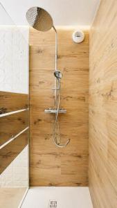 a shower in a bathroom with a wooden wall at Studio Cosy in Coussergues +8 photos