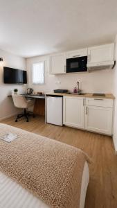 a kitchen with white cabinets and a sink and a table at Studio Cosy in Coussergues