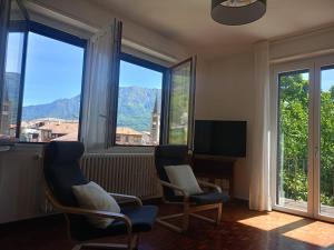 a living room with two chairs and a tv and windows at Casa Silvia Natura Relax, Sport & Family in Omegna