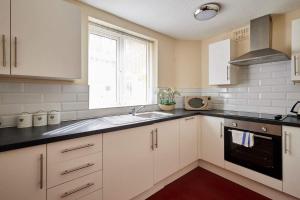 a kitchen with white cabinets and a sink and a window at Host & Stay - Cobblers Cottage in Whitby