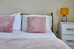 a bed with pink and white pillows and a lamp at Host & Stay - Cobblers Cottage in Whitby
