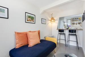 a living room with a blue couch and a kitchen at Casinha Peral Country Cottage in Peral