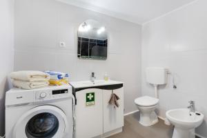 a white bathroom with a washing machine and a toilet at Casinha Peral Country Cottage in Peral +20 photos