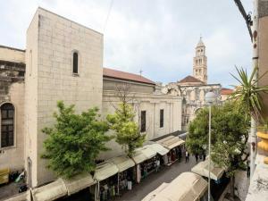 a building with a clock tower and a street with stalls at Silver Gate Rooms-Diocletian's Palace in Split