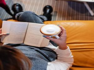 a person reading a book while holding a cup of coffee at Silver Gate Rooms-Diocletian's Palace in Split