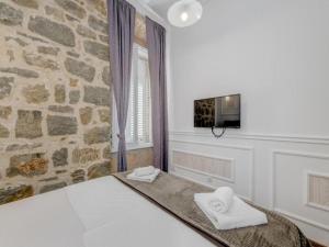 a bedroom with a bed and a stone wall at Silver Gate Rooms-Diocletian's Palace in Split