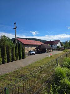 a church with a fence and a car on a road at Happy Family in Suceviţa