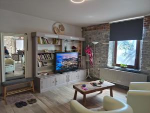a living room with a flat screen tv and a table at Cocoon Hébergement Wellness in Chimay
