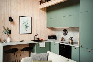 a kitchen with green cabinets and a counter with stools at Rajsco - domek nad Jeziorem Budzisławskim in Tręby Stare