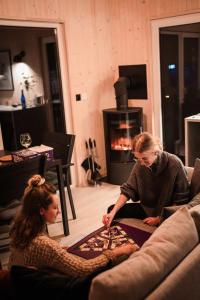 two women sitting on a couch in front of a fireplace at Rajsco - domek nad Jeziorem Budzisławskim in Tręby Stare +28 photos