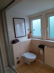 a bathroom with a toilet and two windows at Nordapart Anne Bessrich in Butjadingen