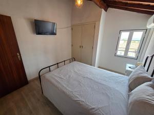 a bedroom with a bed and a tv on the wall at Casa Centro Montargil in Montargil