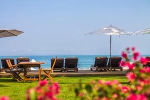 a table and chairs and an umbrella and the ocean at Hotel Spa Nau Royal in Camburi