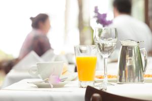 a table with a glass of orange juice and a coffee maker at Hotel Spa Nau Royal in Camburi