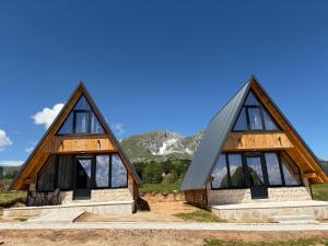 two thatched cottages with mountains in the background at Maple Valley in Žabljak