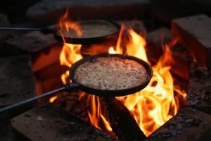 two pans of food on top of a fire at Experience Finland Like a Finn-Private Island Tampere Region in Orivesi