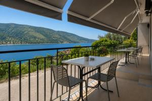 a balcony with tables and chairs and a view of the water at Panorama Plataria Ionio Studios&Apartments in Plataria