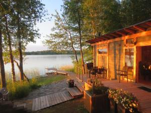 a wooden cabin with a deck next to a lake at Villa Visioduuri in Savonlinna