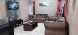 a living room with two couches and a tv at Vuya Nathi Bed and Breakfast in Manzini