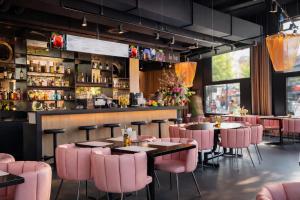 a restaurant with pink chairs and tables and a bar at VISIONAPARTMENTS Wolframplatz - self check-in in Zurich