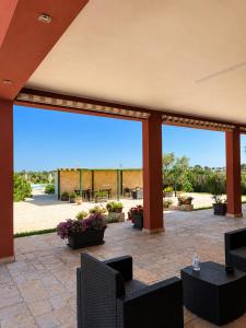 a patio with a large window with chairs and tables at Agriturismo Caranna in Torre Lapillo