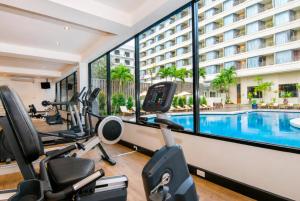 a hotel gym with cardio equipment and a swimming pool at The Bayview Hotel Pattaya in Pattaya