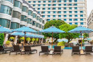 a group of chairs and umbrellas in front of a building at The Bayview Hotel Pattaya in Pattaya +86 photos