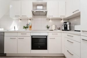 a white kitchen with white cabinets and appliances at Meerzeit Fehmarn in Wulfen auf Fehmarn