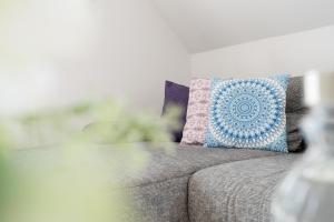 a couch with a blue and pink pillow on it at Meerzeit Fehmarn in Wulfen auf Fehmarn +37 photos