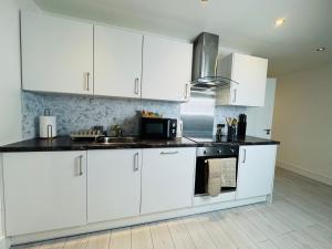 a kitchen with white cabinets and a black counter top at Deluxe One-Bedroom Apartment, Central in Swindon