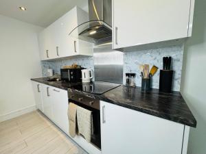 a kitchen with white cabinets and a black counter top at Deluxe One-Bedroom Apartment, Central in Swindon